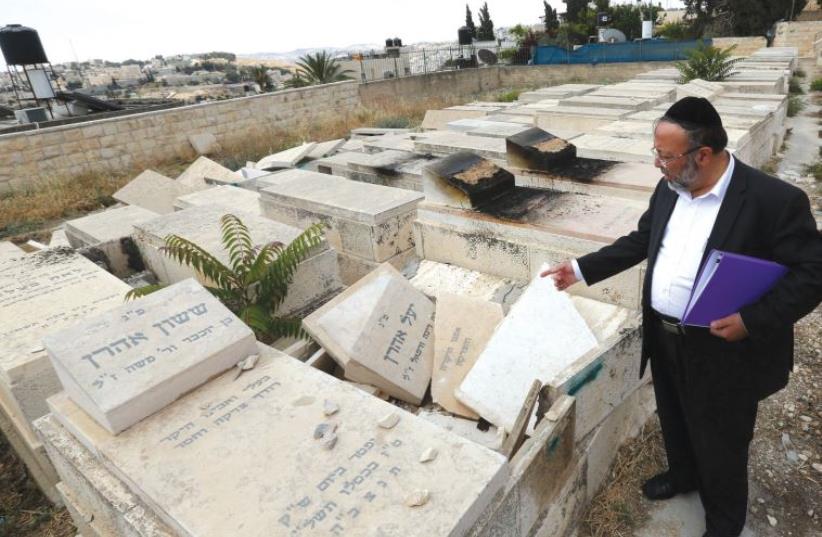 The caretaker of the Afghan section of the Mount of Olives Cemetery points out the vandalism. (photo credit: MARC ISRAEL SELLEM/THE JERUSALEM POST)