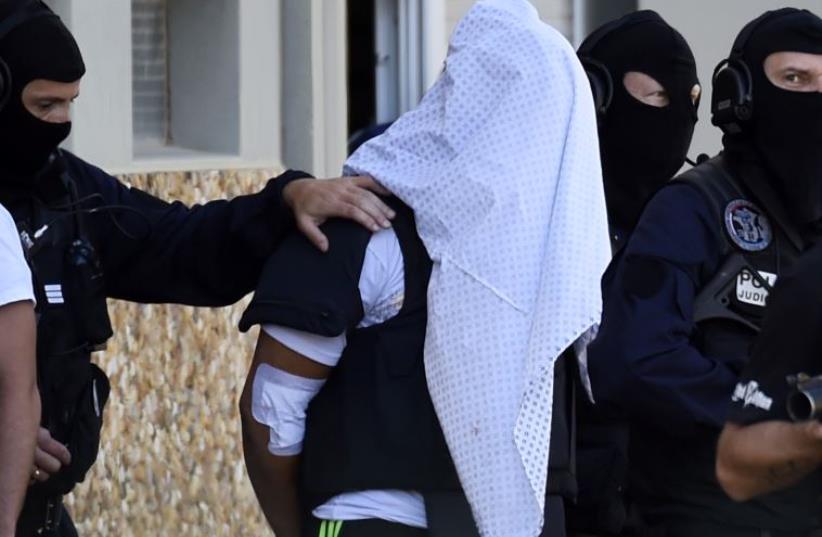 French police escort Yassin Salhi (C), a man suspected of decapitating his boss in an attack on a gas factory, as they leave his flat in Saint-Priest on June 28, 2015 (photo credit: PHILIPPE DESMAZES / AFP)