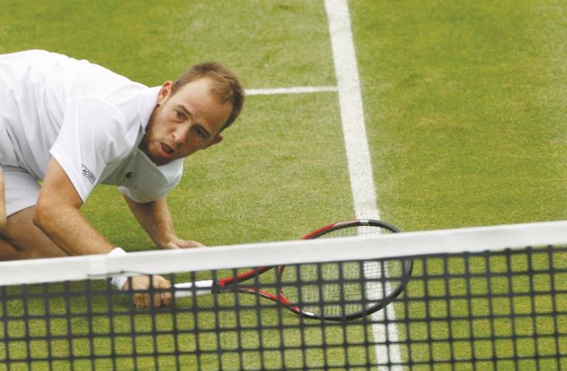 Dudi Sela falls to the grass during his first-round loss at Wimbledon (photo credit: REUTERS)