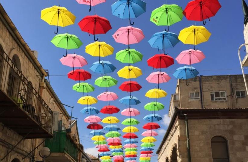 People walk under colourful umbrellas decorating a pedestrian mall in downtown Jerusalem June 30, 2015. (photo credit: CINDY AZOULAY)