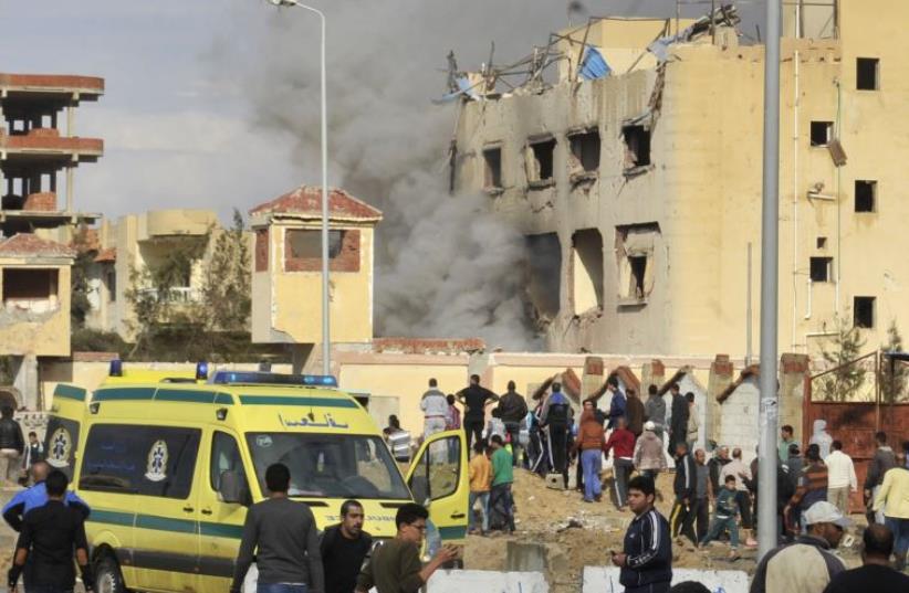 Egyptian residents and emergency personnel gather at the site of a car bomb explosion that targeted a police station in North Sinai's provincial capital of El-Arish on April 12, 2015.  (photo credit: AFP PHOTO)