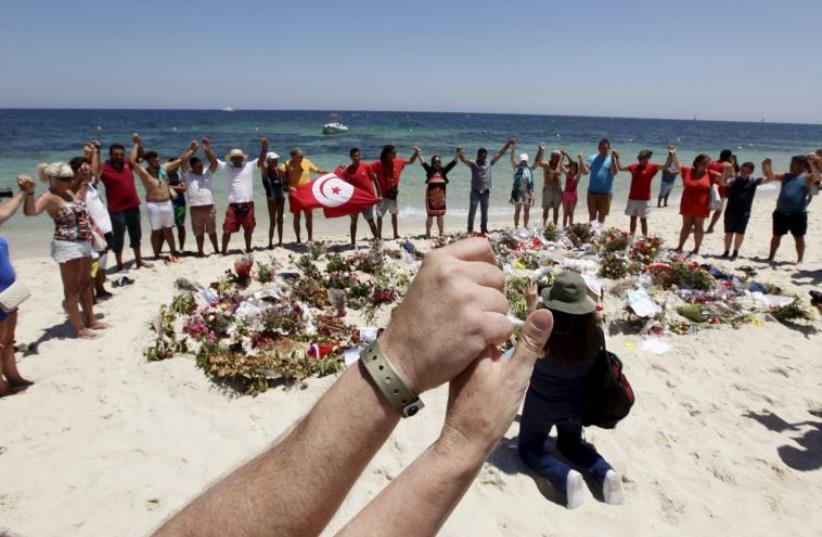 People join hands as they observe a minute's silence in memory of those killed in a recent attack by an Islamist gunman, at a beach in Sousse, Tunisia July 3, 2015. (photo credit: REUTERS/ANIS MILI)