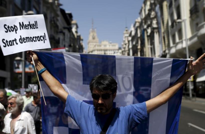 A man holds up a Greek national flag during a demonstration in support of Greece (photo credit: REUTERS)