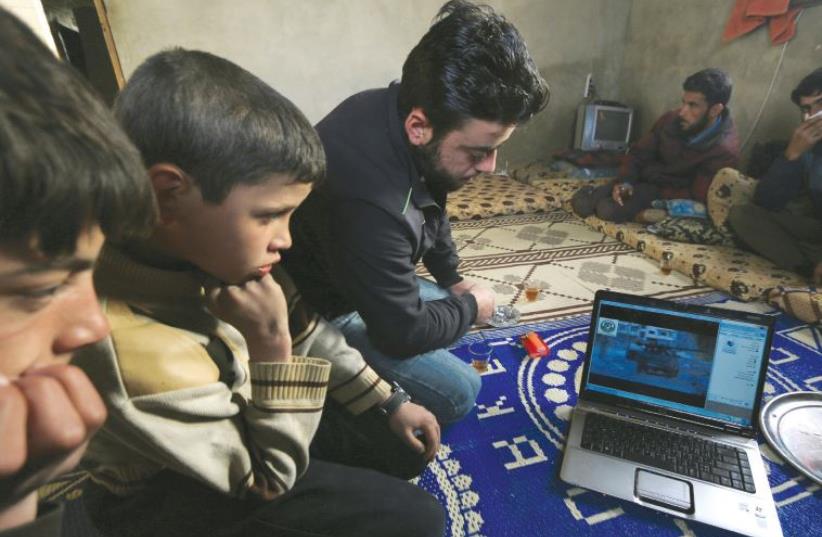 A boy in Syria watches a video on a laptop. (photo credit: ILLUSTRATIVE/KHALIL ASHAWI/REUTERS)