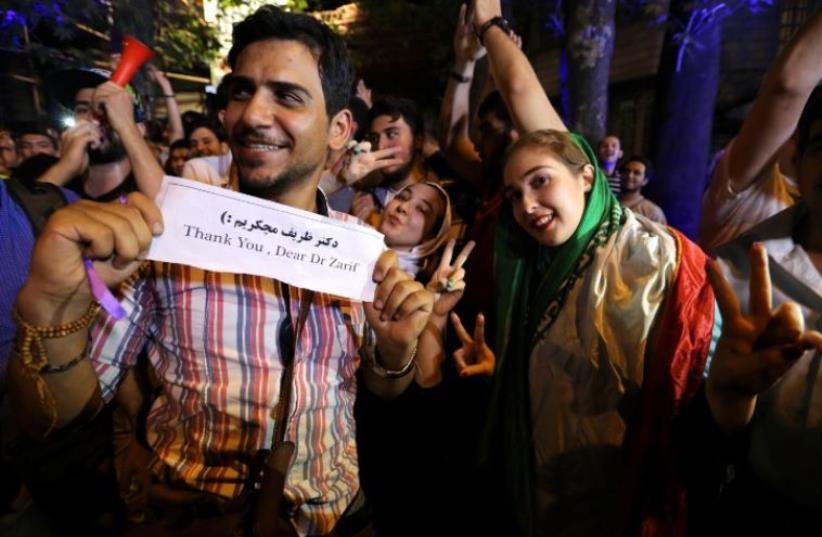 Iranians gather in celebration in northern Tehran on July 14, 2015, after Iran's nuclear negotiating team struck a deal with world powers in Vienna. Iranians poured onto the streets of Tehran after the Ramadan fast ended at sundown Tuesday to celebrate the historic nuclear deal agreed earlier with w (photo credit: ATTA KENARE / AFP)