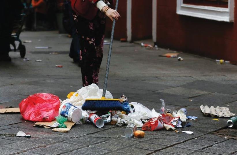 A WOMAN cleans a street. Many asylum-seekers say they have been abused in various ways by employers (photo credit: REUTERS)