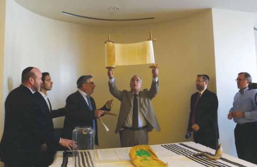 Stuart Steinberg holds the newly finished Torah up for attendees. (photo credit: SARAH LEVI)