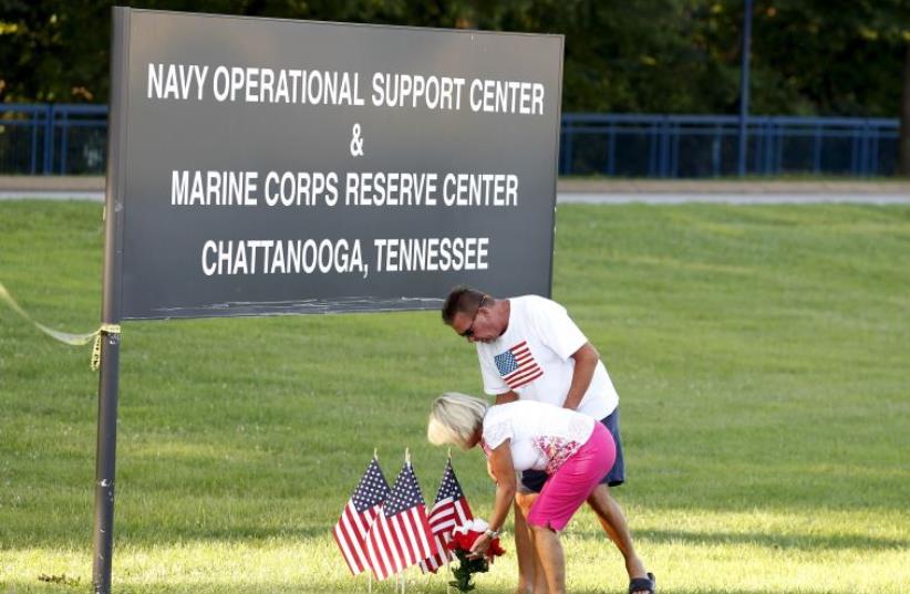 Glenna and Steve Mooneyham place flags and flowers at a sign leading to the Naval Operational Support and Marine Corps Reserve Center in Chattanooga, Tennessee July 16, 2015. (photo credit: REUTERS)