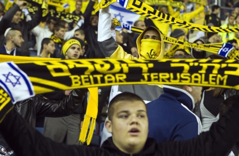 Fans of Beitar Jerusalem shout slogans during a match against Bnei Sakhnin as part of the Israeli Premier League (photo credit: REUTERS)