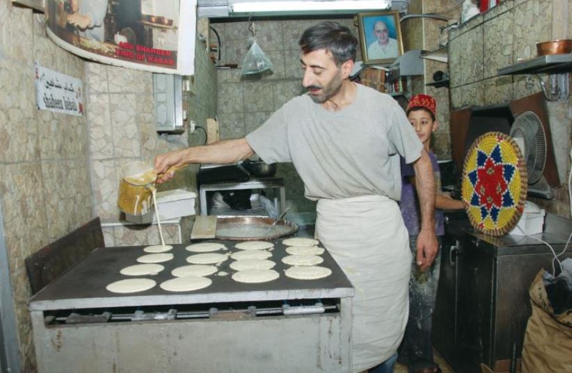 Ghazi Shaheen pours out sweet pancakes, katayef, while (right) his two sons help at the family’s restaurant in the Old City. (photo credit: DUDI SAAD/THE MEDIA LINE)