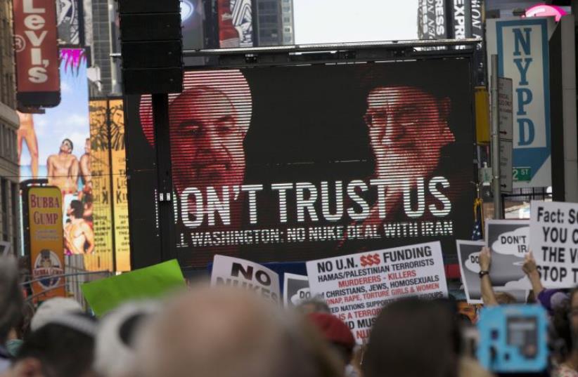 An image of Iranian leaders is projected on a giant screen in front of demonstrators during a rally opposing the nuclear deal with Iran in Times Square, July 22, 2015 (photo credit: REUTERS)