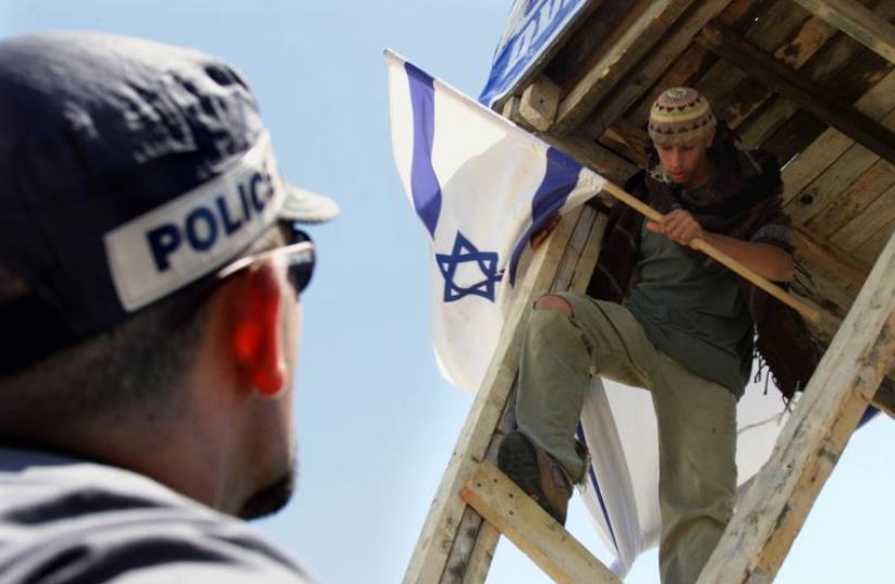 An Israeli policeman tries to talk a young Jewish settler to come down from a tower near Efrat (photo credit: REUTERS)