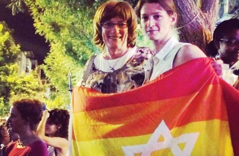 SARAH WEIL (right) and Jewish educator and trans-activist Yiscah Smith wrap themselves in a flag at the rally in Jerusalem Saturday night (photo credit: Courtesy)