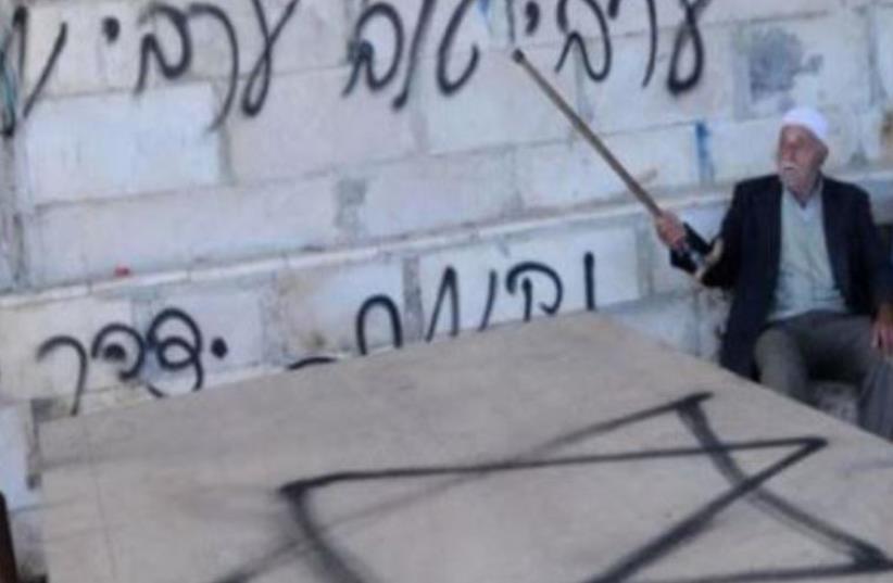 AN ELDERLY Arab man uses his cane to point to hate graffiti spray painted near Damascus Gate , Jerusalem  (photo credit: AL QUDS NEWSPAPER)