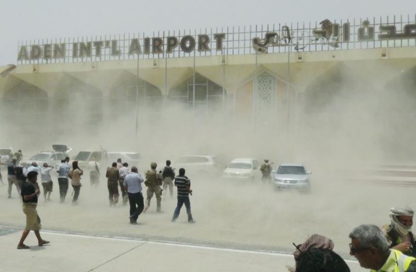 People seek cover from rising dust as a Qatari military cargo plane carrying aid lands at the international airport of Yemen’s southern port city of Aden. (photo credit: REUTERS)