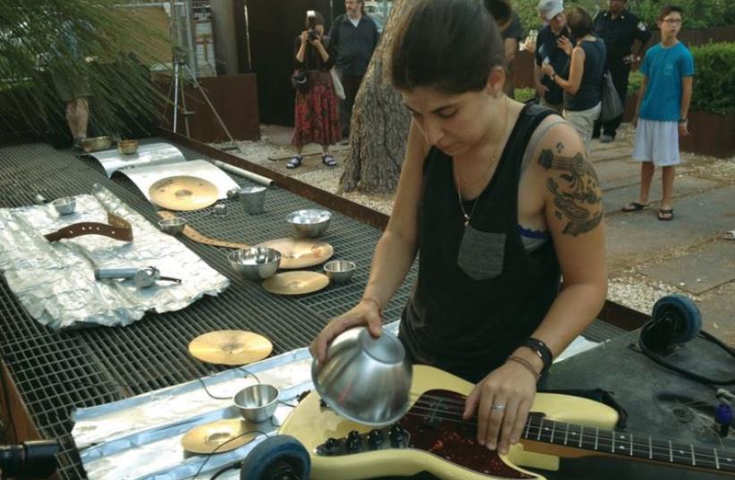 A featured Toolbox artist manipulates an assortment of metal sheets and bowls, in concert with her guitar and audio equipment. (photo credit: JOSH LOGUE)