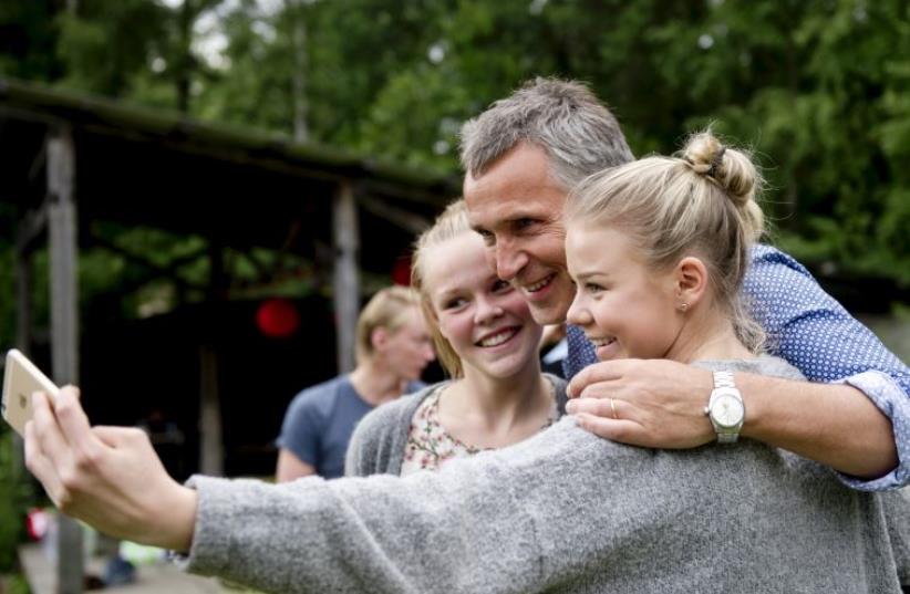 NATO Secretary-General Jens Stoltenberg (C) takes a "wefie" together with two girls during the Labor Youth Organization (AUF) summer camp at Utoya, Norway (photo credit: REUTERS)