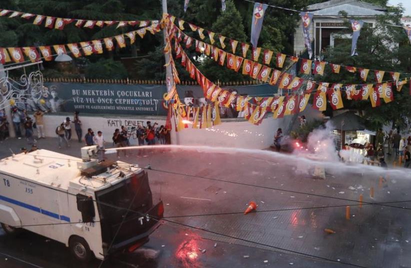 TURKISH RIOT police use water cannon as Kurdish demonstrators throw fireworks during a protest in central Istanbul, July, 2015. (photo credit: REUTERS)