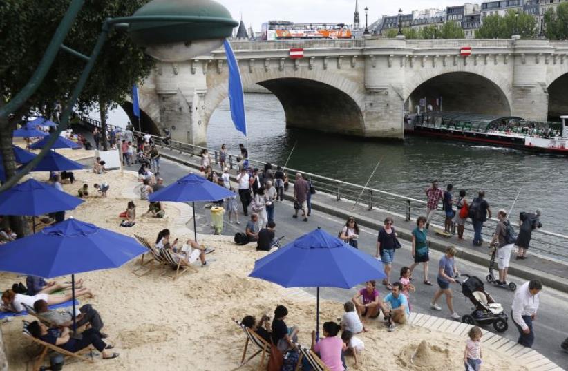 People relax as "Paris Plages" (Paris Beach) opens along the banks of River Seine in Paris, France, July 20, 2015. (photo credit: REUTERS)