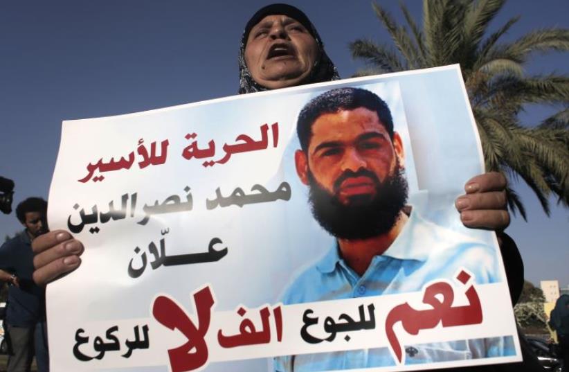 Maazouze, the mother of Mohammed Allaan, a Palestinian prisoner who is on a long-term hunger strike, holds a portrait of her son during a rally calling for his release. (photo credit: AHMAD GHARABLI / AFP)