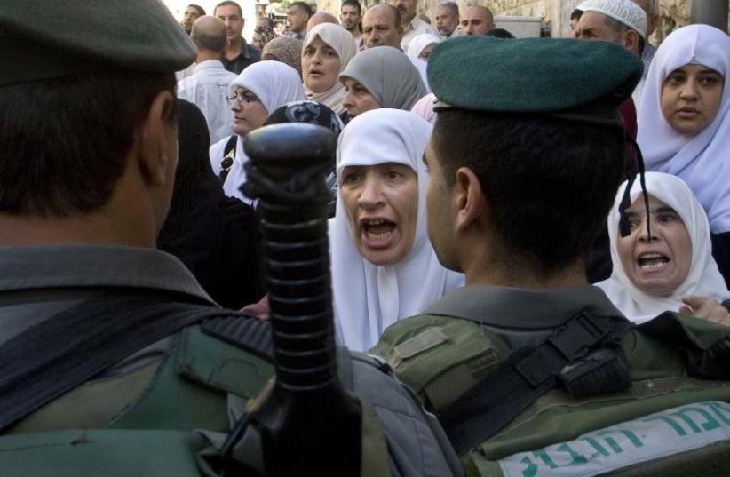 Palestinian women shout in front of Israeli border police officers  (photo credit: REUTERS)