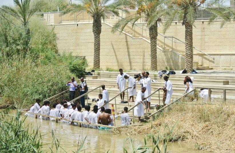 African pilgrims immerse themselves on the Israeli side of the Jordan River. Inset, a view of the Jordanian baptism site on the other side of the river. (photo credit: SETH J. FRANTZMAN/MARC ISRAEL SELLEM/THE JERUSALEM POST)