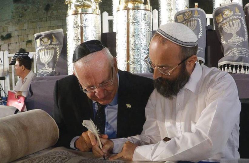 PRESIDENT REUVEN RIVLIN, with the assistance of a scribe, completes a ELIE ESTRIN (Courtesy Chabad) letter in one of the Torah scrolls dedicated at the Western Wall this week in memory of fallen soldiers.  (photo credit: Mark Neiman/GPO)