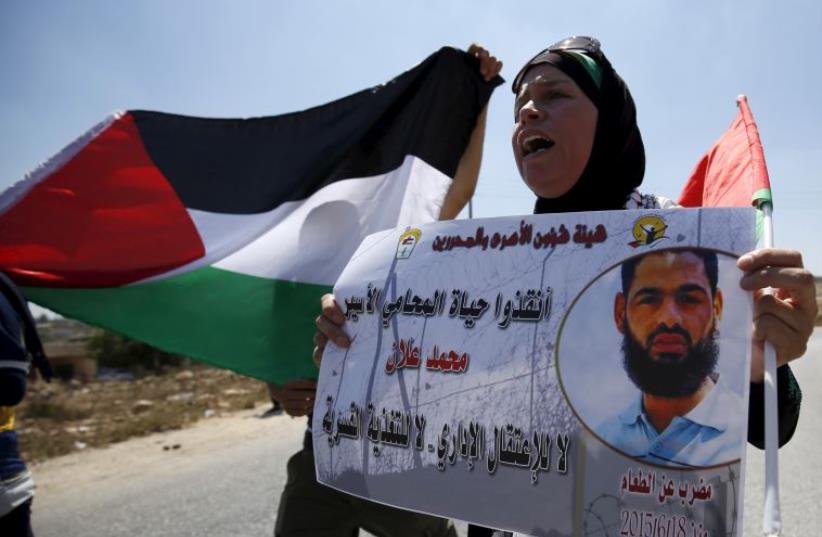 A Palestinian woman holds a picture depicting Palestinian detainee Mohammed Allan during a protest in solidarity with Allan in the West Bank village of Nabi Saleh (photo credit: REUTERS)