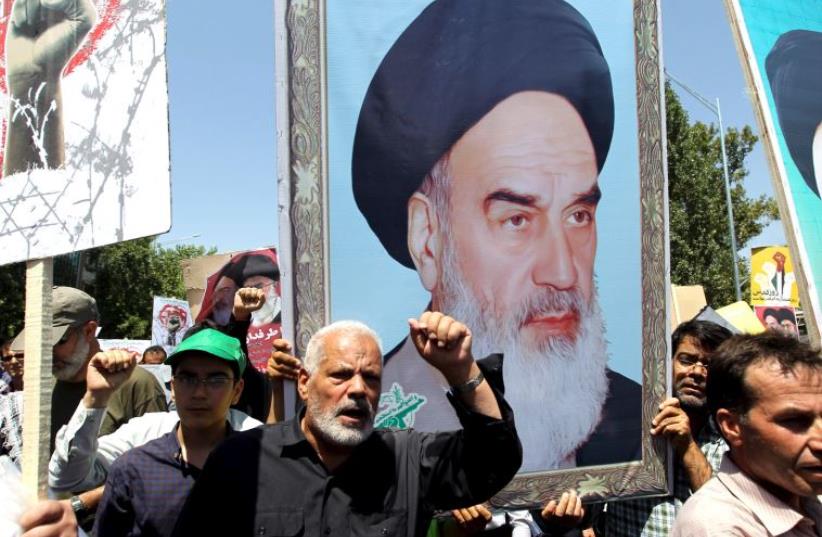 Demonstrators shout slogans in front of a poster depicting Iran's late leader Ayatollah Khomeini during a rally in Tehran (photo credit: REUTERS)