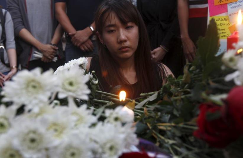 A woman lights a candle at the Erawan shrine, the site of Monday's deadly blast, in central Bangkok (photo credit: REUTERS)