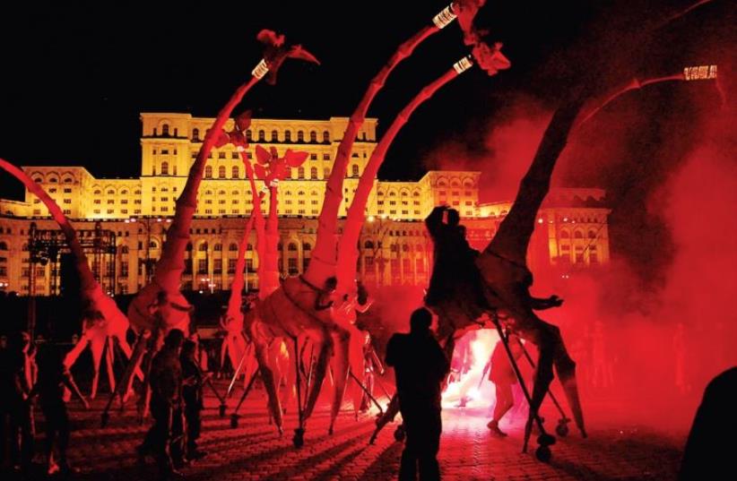‘Les Girafes’ by the Compagnie Off street arts gang incorporates red, eight-meter versions of the towering beast, augmented by the vocals of an opera singer. (photo credit: YACHATZ)