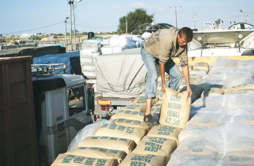 A Palestinian lays out sacks of cement allowed into Gaza by Israel. (photo credit: REUTERS)
