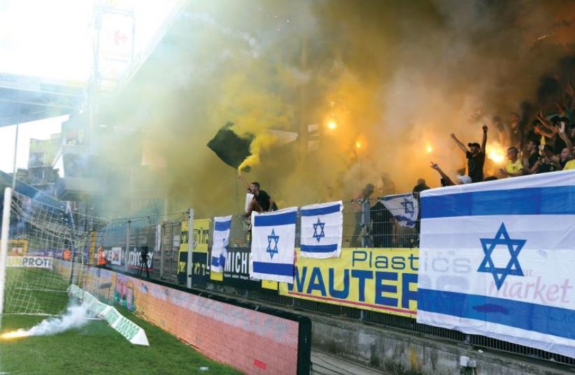 Jerusalem supporters from the La Familia fan group hold up a match against Charleroi in Belgium (photo credit: UDI ZITIAT)