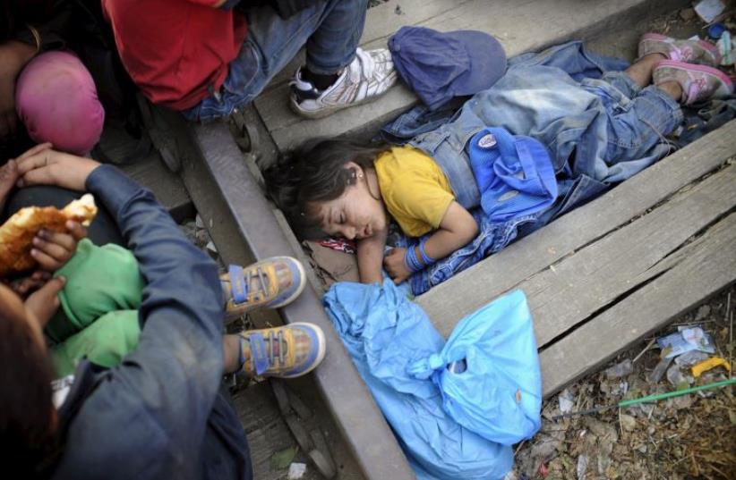 Four-year-old Rashida from Kobani, Syria, part of a new group of more than a thousand immigrants, sleeps as they wait at border line of Macedonia and Greece to enter into Macedonia (photo credit: REUTERS)