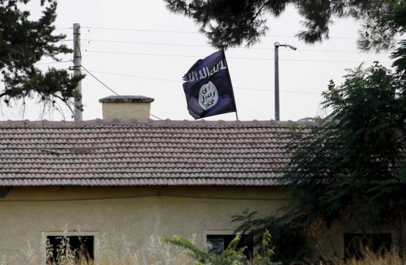 An Islamic State flag flies over the custom office of Syria's Jarablus border gate as it is pictured from the Turkish town of Karkamis (photo credit: REUTERS)