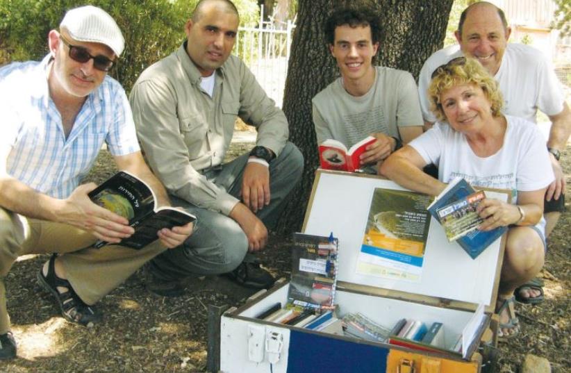 REPRESENTATIVES OF the Shalem Center, the Israel Nature and Parks Authority along with trail hikers Nirit Leshem and Roi Sokolovski, pose with a ‘trail library.’ (photo credit: COURTESY SHALEM CENTER)