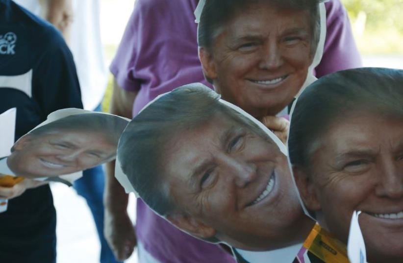 Cutouts of US Republican presidential candidate Donald Trump are held by supporters waiting in line outside a campaign town hall meeting in Derry, New Hampshire, (photo credit: BRIAN SNYDER / REUTERS)