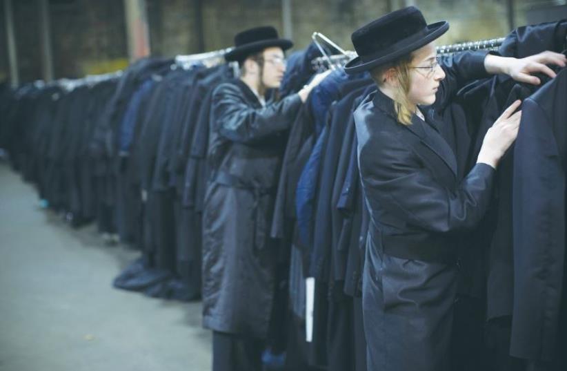 MEN SEARCH the cloak room for their jackets at a mass gathering of Satmar Hassidim in New York (photo credit: REUTERS)