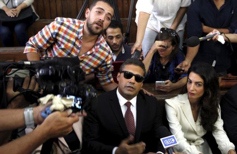 Al Jazeera television journalists Mohamed Fahmy, and Baher Mohamed, talk to the media with lawyer Amal Clooney before hearing the verdict at a court in Cairo. (photo credit: REUTERS)