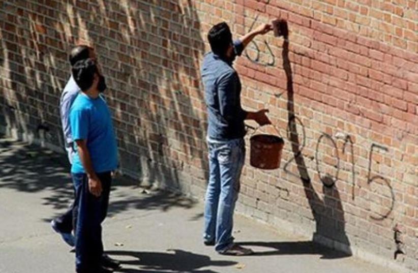 Iranians erase 'Death to America' graffiti from wall of former US Embassy in Tehran‏ (photo credit: IRANIAN MEDIA)