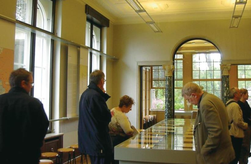 Visitors to the Wannsee House look at copies of the meeting’s minutes in the conference room. (photo credit: Wikimedia Commons)