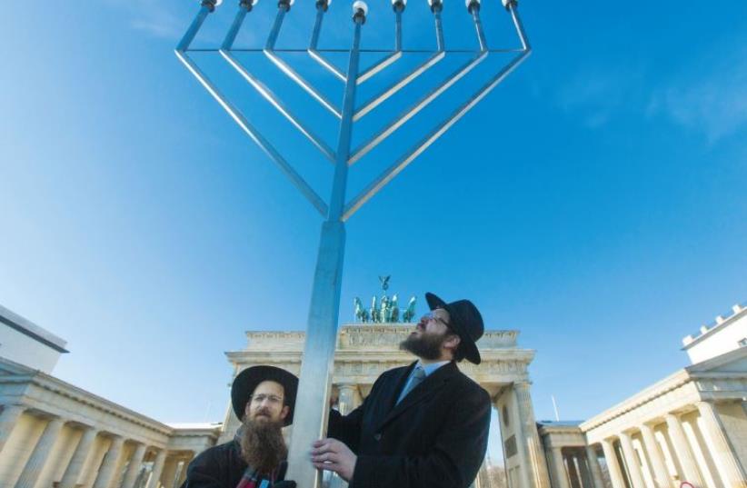 Chabad Rabbis Shmuel Segal and Yehuda Teichtal light Hanukka candles in front of the Brandenburg Gate in Berlin in 2012 (photo credit: THOMAS PETER/REUTERS)
