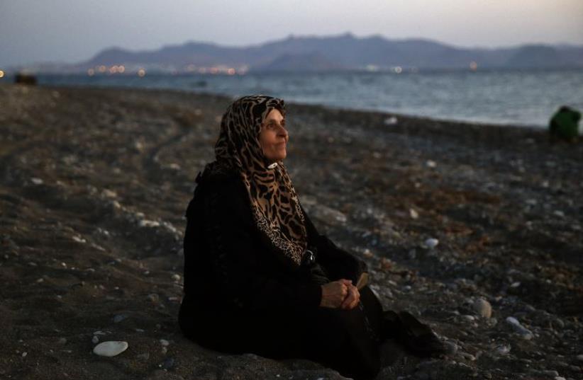 Amoun, 70, a blind Palestinian refugee who lived in the town of Aleppo in Syria, rests on a beach moments after arriving along with another forty on a dinghy in the Greek island of Kos (photo credit: REUTERS)