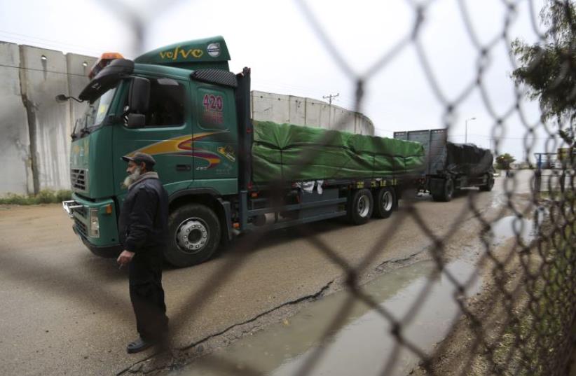 A Palestinian policeman stands guard as a truck loaded with fruits and vegetables waits to cross into the Israeli side of the Kerem Shalom crossing in Rafah (photo credit: REUTERS)