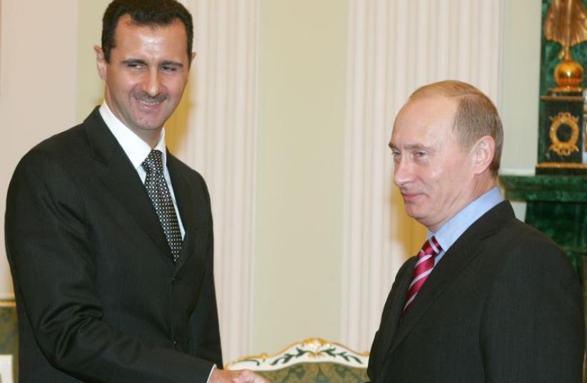 Russia's President Vladimir Putin (R) and Syrian President Bashar Assad shake hands as they meet in the Kremlin (photo credit: REUTERS)