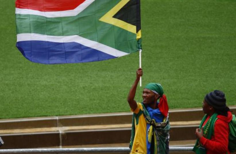 A man raises the South African national flag during the service for former South African President Nelson Mandela at the First National Bank Stadium (photo credit: REUTERS)
