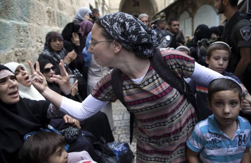 An Israeli woman and a Palestinian woman gesture at one another during a protest  (photo credit: REUTERS)
