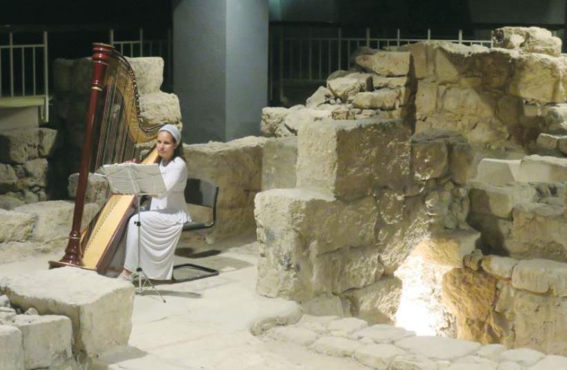 A woman plays the harp among excavations as part of holiday visits (photo credit: MEITAL SHARABI)