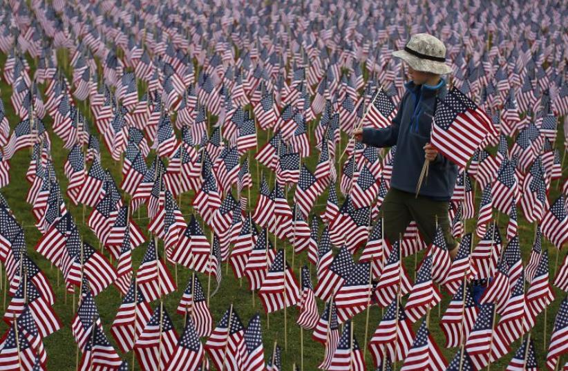 Boy among some of the 3,000 flags placed in memory of lives lost in the September 11, 2001 attacks, at park in Winnetka, Illinois, September 10, 2015. (photo credit: REUTERS)