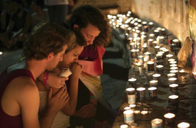YOUTH SIT next to candles last month during a vigil in Tel Aviv for Shira Banki, who died of stab wounds sustained when a man with a knife attacked a Gay Pride parade in Jerusalem (photo credit: REUTERS)